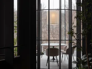 A modern dining area with a round glass table surrounded by four chairs, set in a well-designed interior