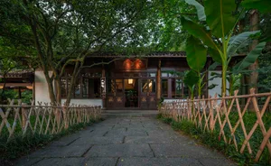 Serene Asian courtyard with a wooden fence, a large doorway, and chairs placed around the area