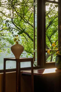 A bright and inviting living space with a large window, vases, and a potted plant, flooded with natural light