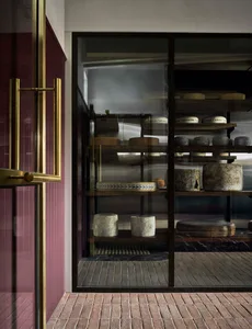 A well-organized cheese shop with a glass display case showcasing a variety of cheeses in different shapes, sizes, and colors