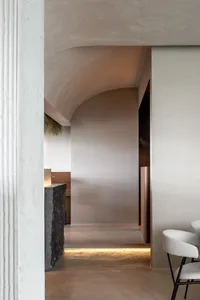 A modern hallway with a curved wall, two chairs, and a dining table, creating a unique and well-designed space