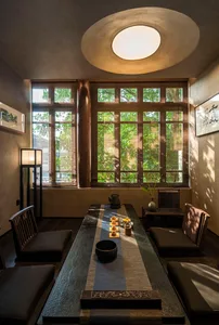 Bright and welcoming living room with large windows, two couches, a dining table, chairs, and a bowl on the table