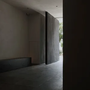 Dimly lit hallway with concrete floor, two doors on either side, and a quiet atmosphere