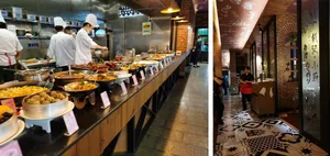 Industrial kitchen with a brick wall, a long buffet table filled with various food items and bowls, and a restaurant or cafeteria atmosphere