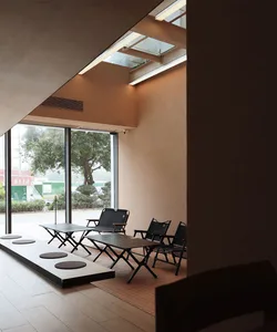 A cozy indoor space with chairs arranged in a lobby or waiting area, featuring concrete walls and a modern industrial feel