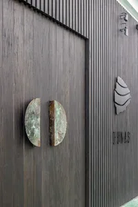 一扇風化木門兩側各有一圓形金屬板，營造傳統歷史氛圍