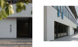 A modern building with a white exterior and a large glass window that allows natural light to enter the interior