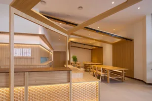 Modern restaurant interior with wooden floors and walls, featuring multiple dining tables and chairs in a comfortable and inviting atmosphere