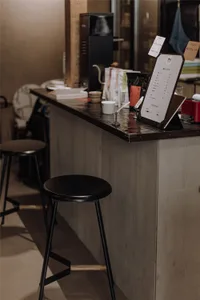 Inviting cafe interior with a counter, stools, and books, featuring a menu board and various items on display