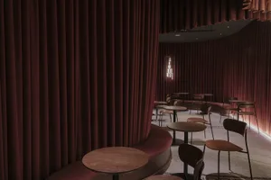 Cozy restaurant interior with red curtains, wooden tables, and comfortable seating