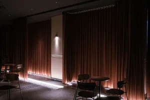 A cozy restaurant dining area with multiple chairs and tables, curtains, and warm lighting