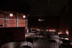 Cozy restaurant dining area with multiple tables and chairs, warm wooden walls, and a mix of ambient and task lighting