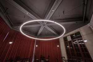 A warm and inviting restaurant interior with a circular light fixture, chairs, and dining tables, creating a cozy atmosphere for patrons