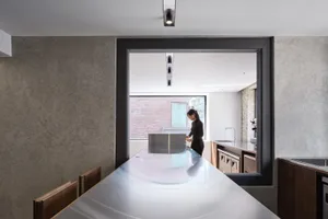 A cozy kitchen with a dining table and chairs, a sink, and a refrigerator, with two people present