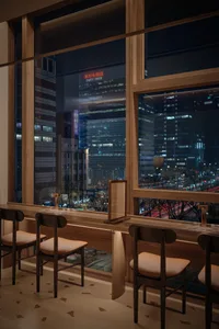 優雅餐廳內裝，融入現代設計元素、座椅，並透過大片窗戶欣賞夜晚璀璨的城市天際線