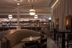 A cozy bar area with a long wooden dining table and chairs, a bar counter with bottles and wine glasses, and an inviting atmosphere