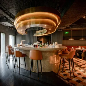 A modern bar area with a circular countertop, stools, bottles, cups, and wine glasses, set in a sophisticated and inviting atmosphere