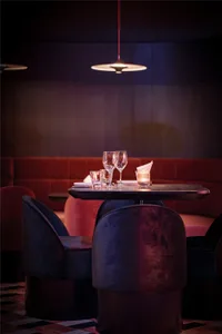 現代餐廳內部，設有兩張餐桌、椅子、酒杯與餐巾，營造時尚而溫馨的氛圍