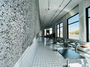Empty modern restaurant with white tile floor, large window, and dining tables and chairs