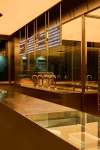Industrial kitchen with stainless steel counters, multiple sinks, and bottles on countertops, conveying a clean and organized atmosphere