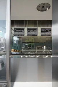 Industrial kitchen with a stainless steel countertop, utensils, and bottles, featuring a clean and organized atmosphere with a focus on functionality and efficiency