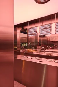 Industrial kitchen with stainless steel surfaces, two sinks, and various kitchen utensils and supplies