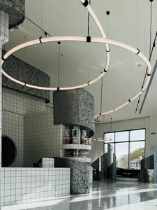 Modern dining space with a circular light fixture, counter, chairs, and dining table, surrounded by bottles and a clock on the wall