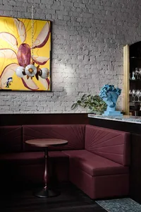 Cozy living space with a purple couch, brick walls, vases, and wine glasses