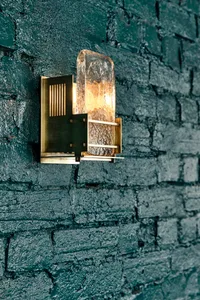 A dimly lit room with an exposed brick wall and two different light fixtures, one with a glass covering and the other a simple metal fixture