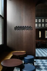 Warm and inviting restaurant interior with wooden walls and floors, featuring two dining tables, chairs, and benches, creating a cozy atmosphere