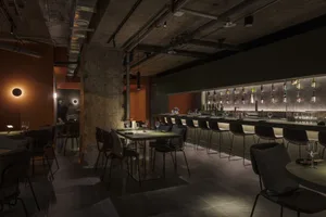 A cozy restaurant interior with a long dining table surrounded by chairs, wine glasses, and an inviting atmosphere
