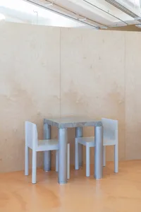 Empty dining area with two white chairs and a small metal table in a minimalist space with clean lines and no additional decorations