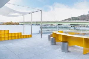 A cozy open area with a wooden table surrounded by metal stools and a bench, creating a comfortable seating space