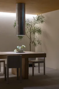 Warm and inviting dining area with a wooden table, chairs, and a vase with flowers as a centerpiece