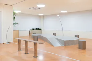 A calm and inviting lobby with a large window, two benches, and potted plants, providing a comfortable space for people to gather and relax