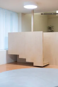 Office space with wooden walls, floors, and partitions, featuring modern furniture and a functional atmosphere