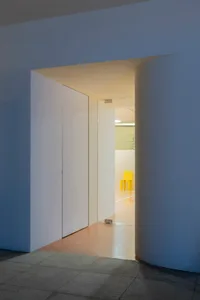 A calm and inviting white room with a yellow chair and wooden floor, minimalist design