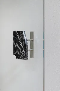 Bathroom with marble countertop, black marble design, and towel racks on either side of the wall