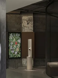 A modern interior space with a white pillar in the center, featuring two posters on the wall with a minimalist design