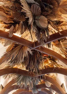 A visually appealing arrangement of straw elements resembling a ceiling or sculpture, with a warm and inviting atmosphere reminiscent of tropical or coastal environments