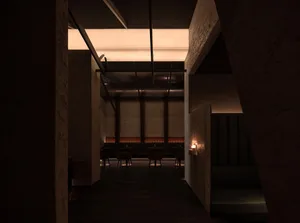 A modern restaurant with wood paneling, multiple tables, chairs, and couches, creating a warm and inviting atmosphere
