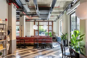 Modern restaurant interior with a dining area, potted plants, and comfortable seating