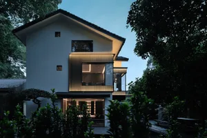 A large white house with multiple windows and doors, featuring a mix of concrete and wood materials, in a well-lit and spacious modern design