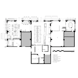 2D floor plan of a modern restaurant with various rooms and spaces labeled, featuring clear lines, minimalistic design, and predominantly white materials