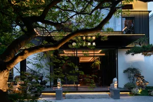 Elegant Asian-style building with a black facade, featuring a large window and statues in front