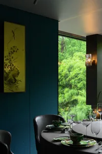A warm and inviting dining area with a table set for dinner, surrounded by comfortable chairs, vases, potted plants, and books