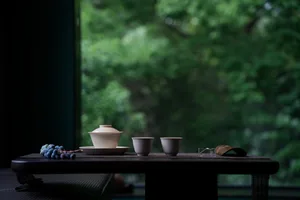A wooden dining table with a tea set and a view through the window