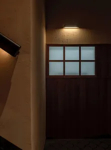 A dimly lit hallway with a wooden door and a window with glass panes, creating a mysterious atmosphere