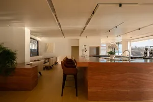 Warm and inviting kitchen and dining area with wooden floors and walls, featuring a dining table, bar counter, and various decorative items