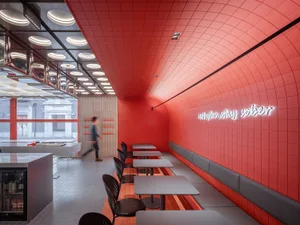 A modern restaurant interior with red walls, tables, and chairs, creating a welcoming atmosphere for guests
